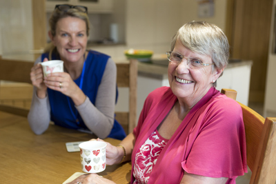 A resident and a carer at greensleeves care home sitting together and enjoying a cup of tea